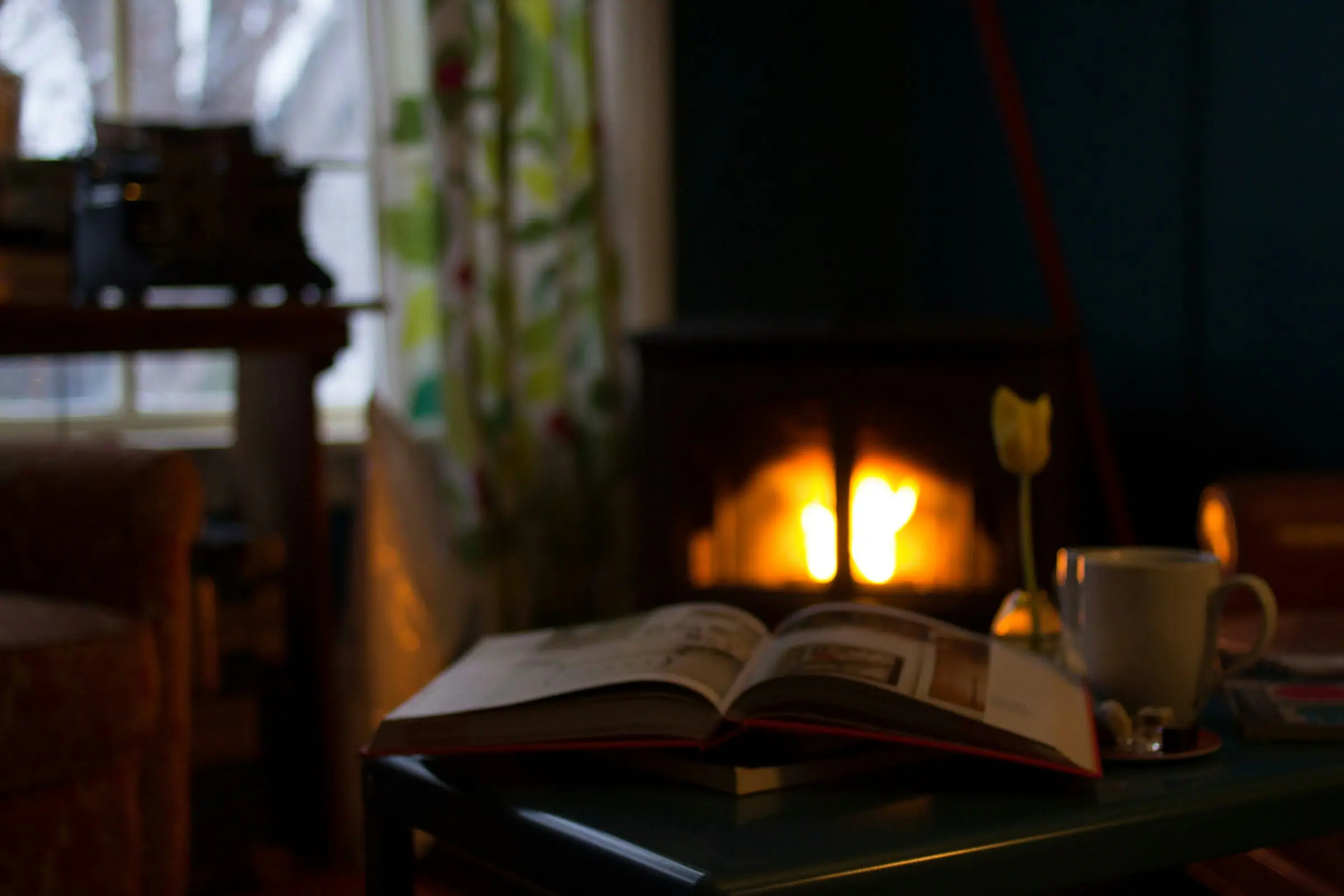 A warm evening reading corner with soft firelight and candles