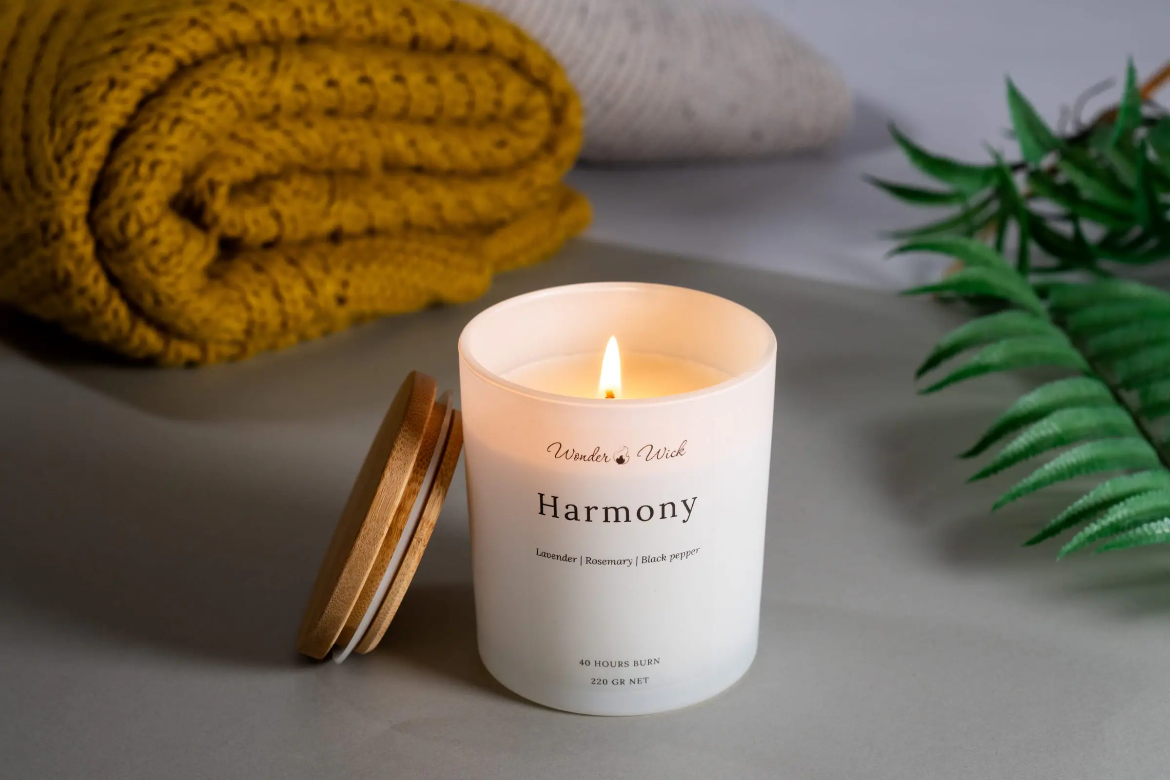 A lit Harmony candle creating soft light beside a basket at home