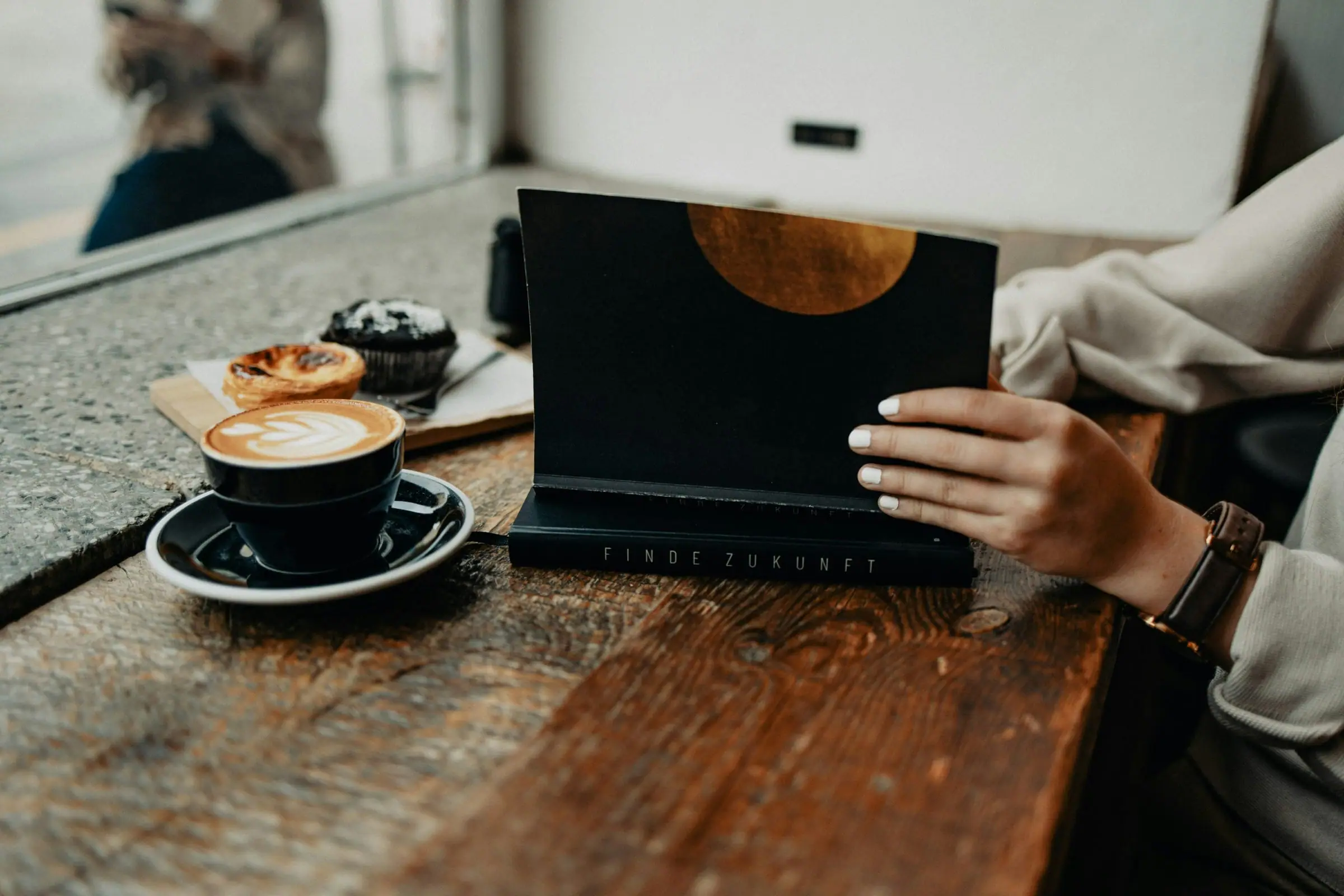 A laptop, coffee and notebook prepared on a home desk