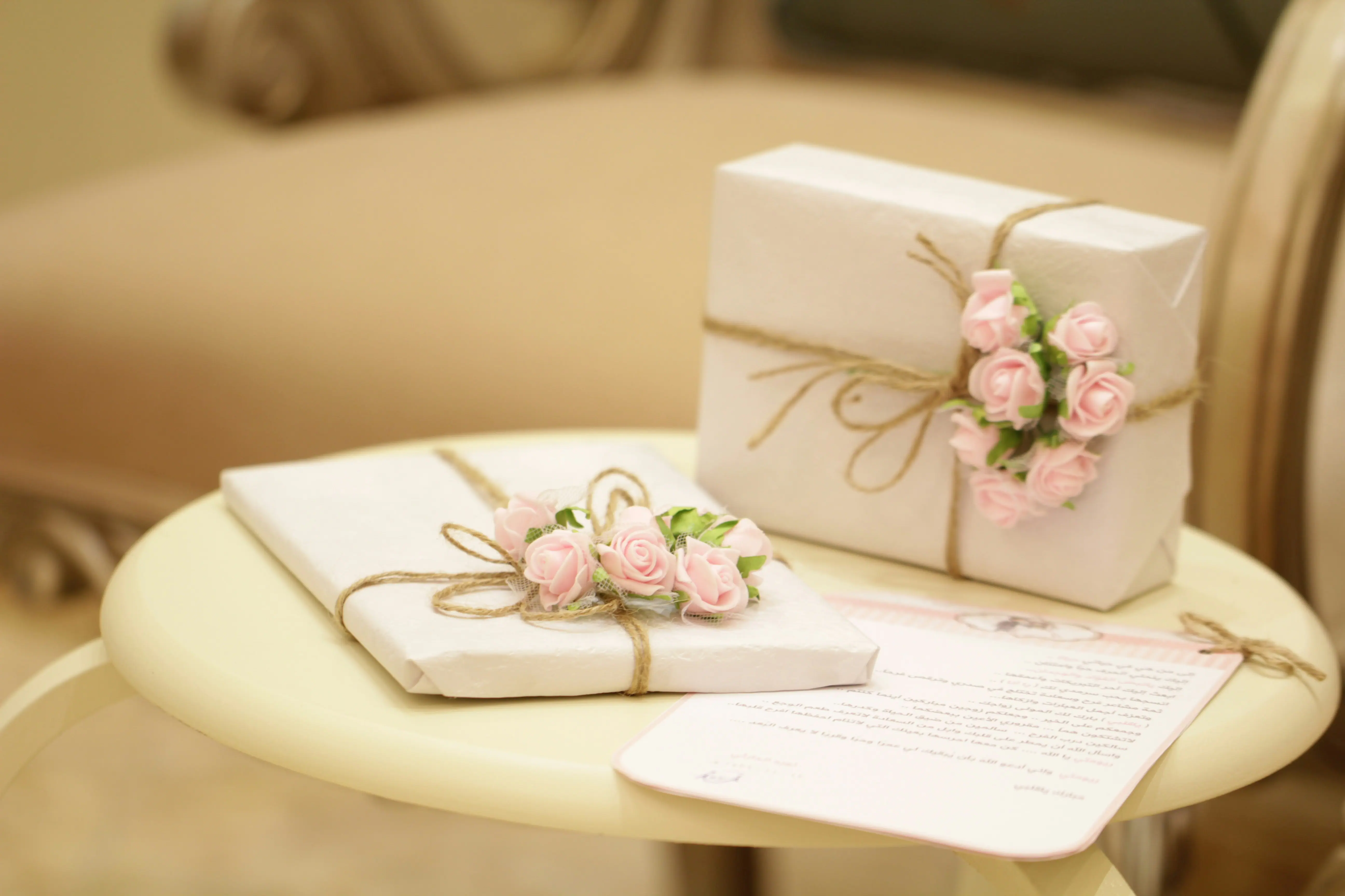 Wrapped gift boxes decorated with pink roses beside a handwritten card