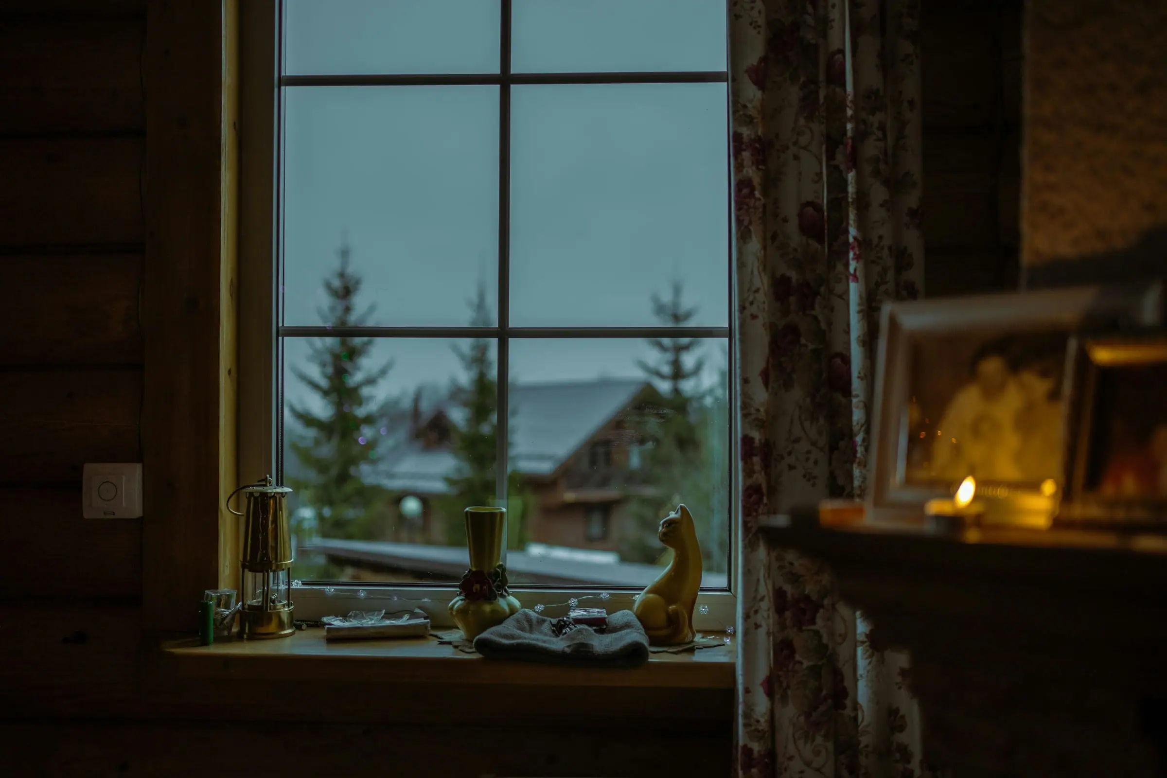 Candle glowing on a windowsill in a quiet room in the evening
